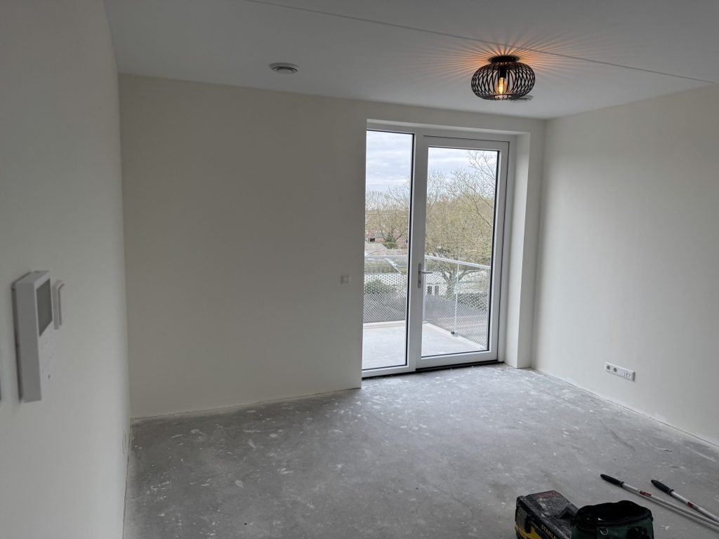 Pas opgeleverde nieuwbouwkamer met balkondeur en kale lichte wanden